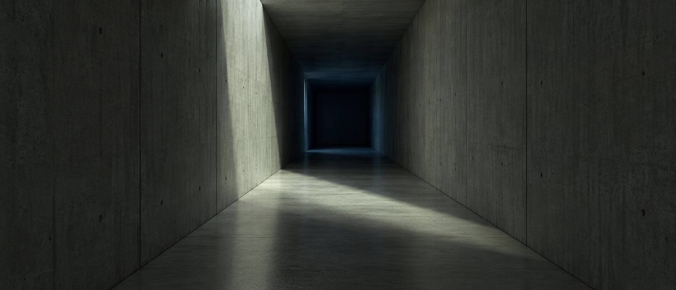 A concrete corridor crossed by a shaft of light